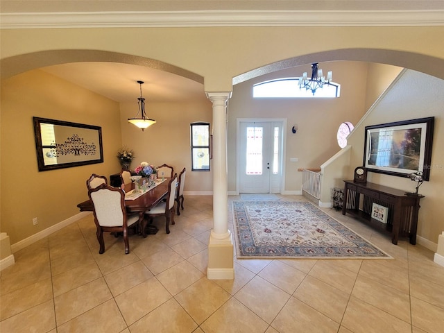 entrance foyer featuring an inviting chandelier, light tile patterned flooring, crown molding, and ornate columns