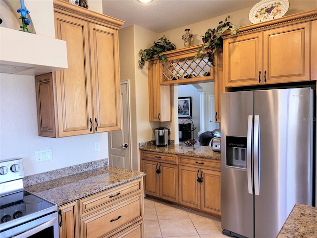 kitchen featuring light stone counters, stainless steel fridge, light tile patterned floors, and range with electric cooktop