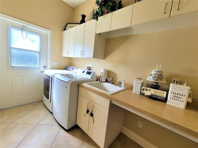 washroom featuring cabinets, sink, light tile patterned flooring, and washing machine and dryer