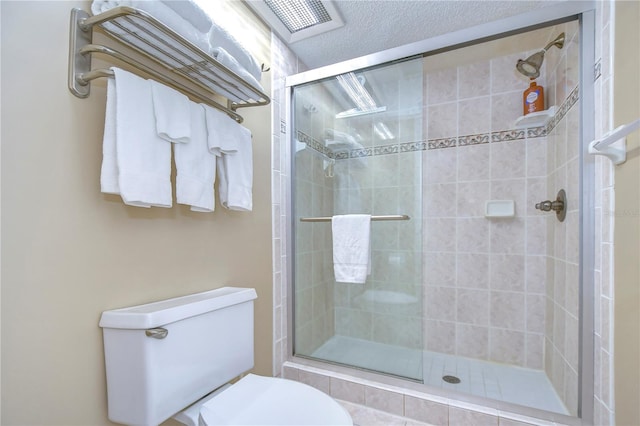 bathroom featuring walk in shower, toilet, and a textured ceiling