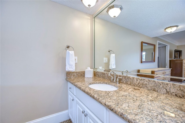 bathroom featuring a textured ceiling, large vanity, and ornamental molding