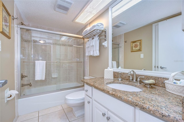 full bathroom with vanity with extensive cabinet space, shower / bath combination with glass door, tile flooring, toilet, and a textured ceiling