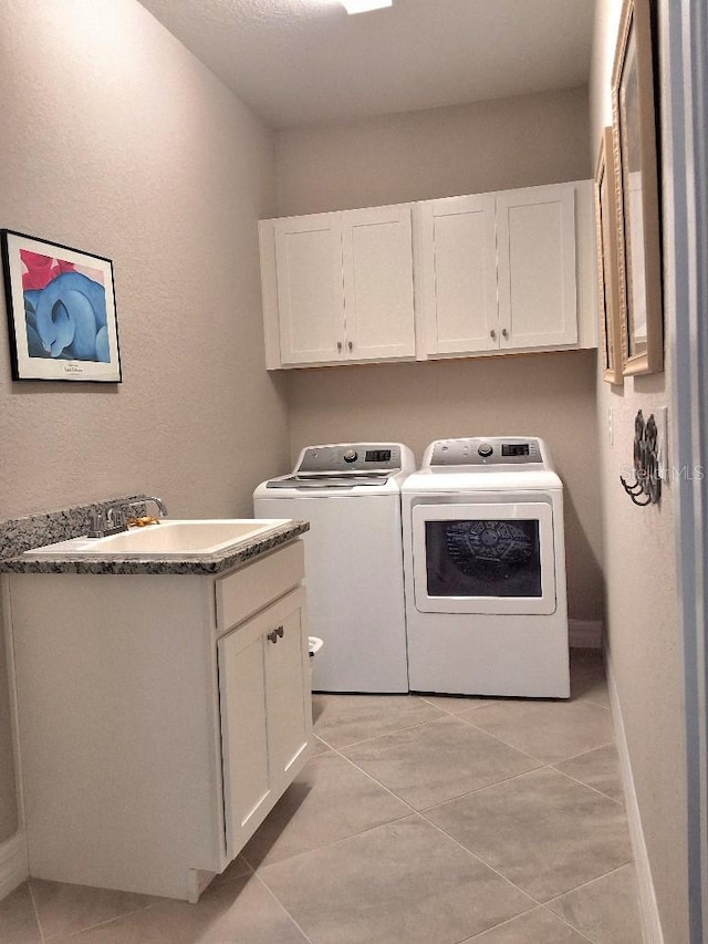 clothes washing area with sink, independent washer and dryer, light tile floors, and cabinets