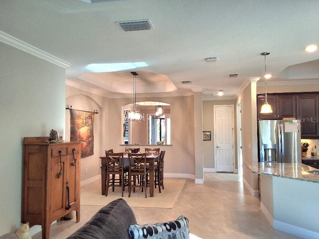 living room featuring decorative columns, a textured ceiling, an inviting chandelier, light tile floors, and ornamental molding