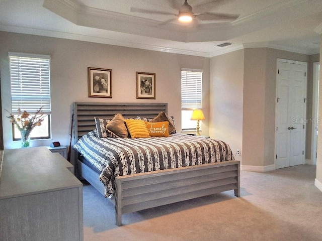 carpeted bedroom featuring ornamental molding, ceiling fan, and a raised ceiling