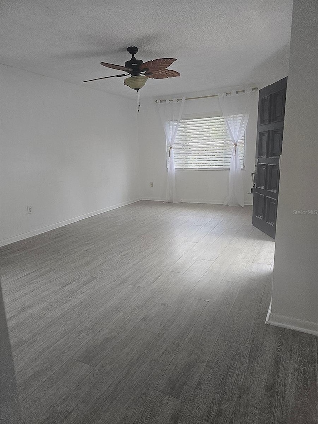 spare room featuring baseboards, a textured ceiling, a ceiling fan, and wood finished floors