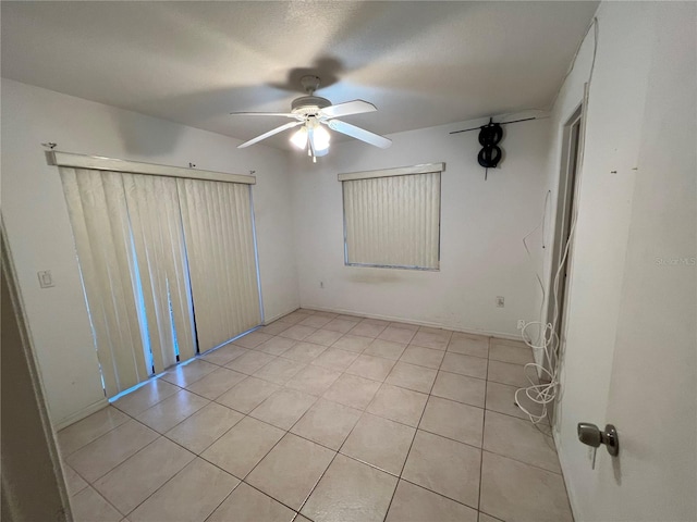 spare room with ceiling fan and light tile floors