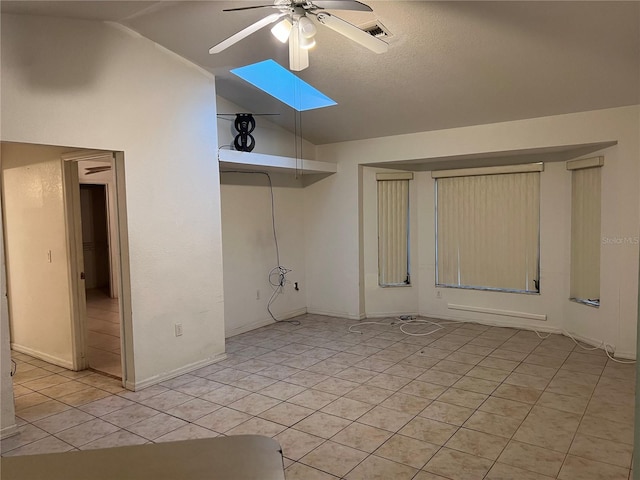 tiled spare room featuring ceiling fan and vaulted ceiling with skylight