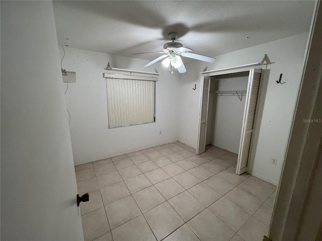 unfurnished bedroom with a closet, ceiling fan, and light tile flooring