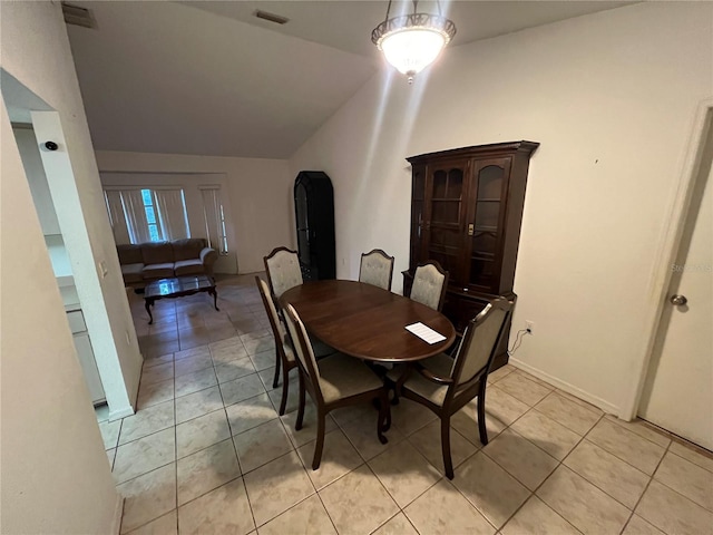 tiled dining room featuring lofted ceiling