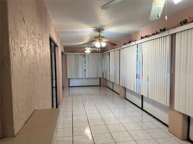 interior space featuring a textured ceiling, ceiling fan, and light tile flooring