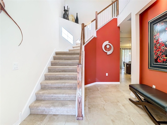 staircase featuring tile floors and a high ceiling