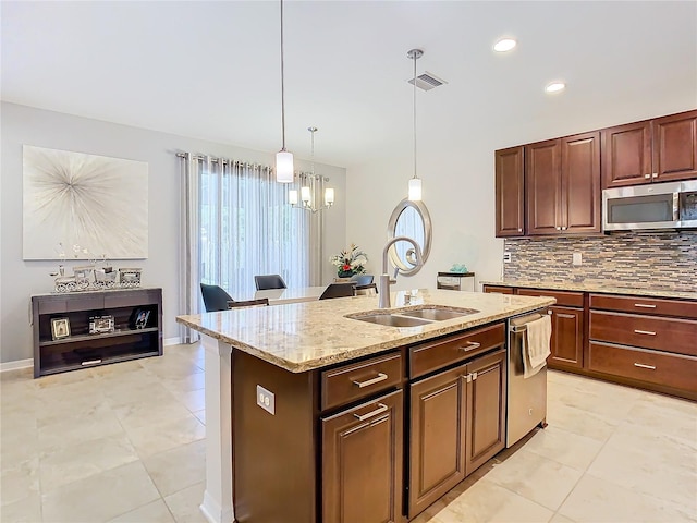 kitchen featuring decorative light fixtures, appliances with stainless steel finishes, a center island with sink, light tile floors, and sink