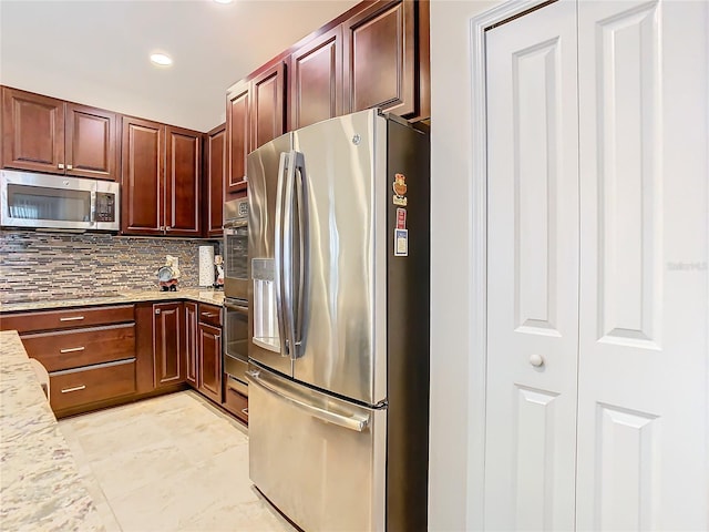 kitchen featuring tasteful backsplash, appliances with stainless steel finishes, light stone counters, and light tile flooring