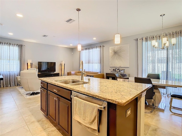 kitchen with stainless steel dishwasher, hanging light fixtures, a kitchen island with sink, and a wealth of natural light