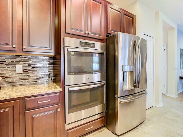 kitchen featuring backsplash, light stone countertops, stainless steel appliances, and light tile flooring