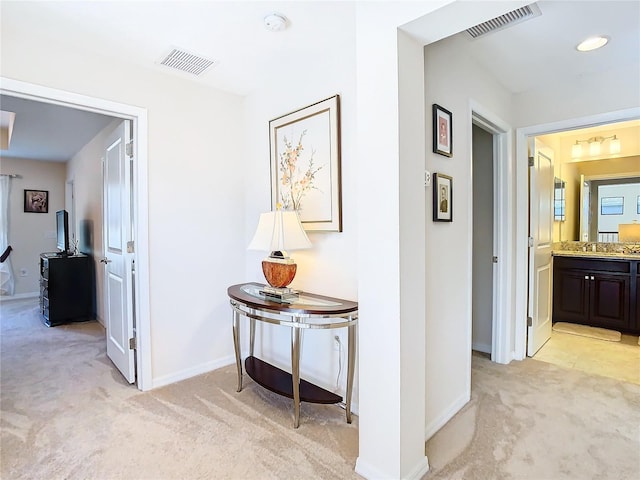 corridor featuring sink and light carpet