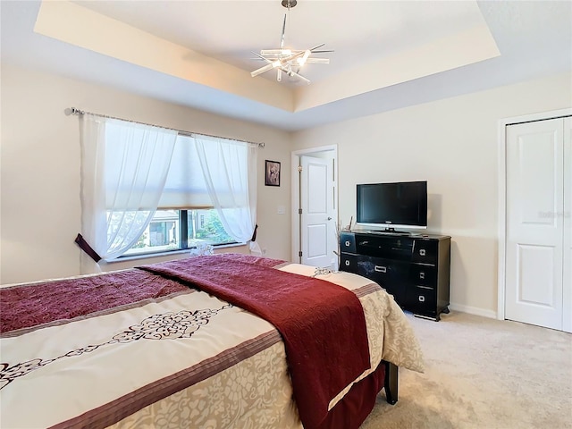 carpeted bedroom featuring ceiling fan and a tray ceiling