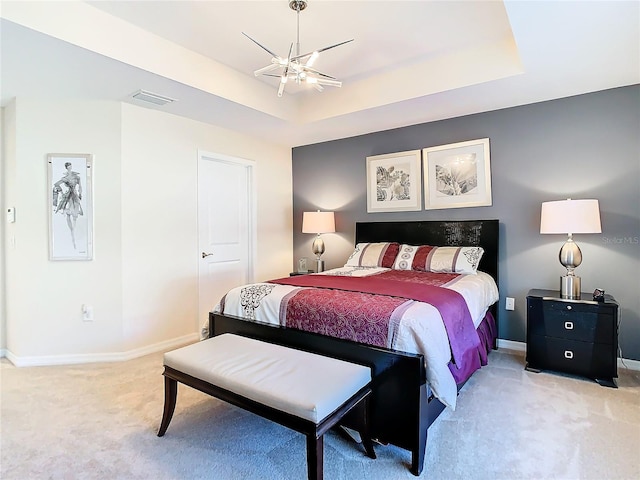 carpeted bedroom with ceiling fan and a raised ceiling