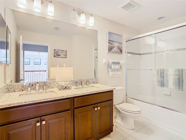 full bathroom featuring tile floors, large vanity, double sink, bath / shower combo with glass door, and toilet