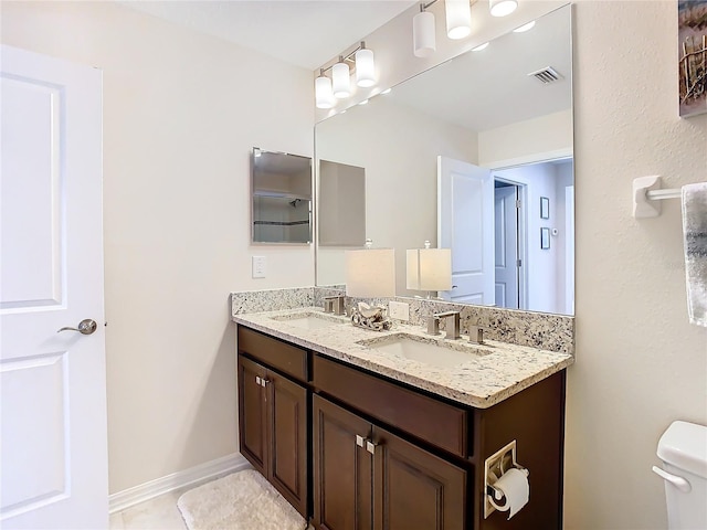 bathroom featuring tile floors, toilet, and dual vanity