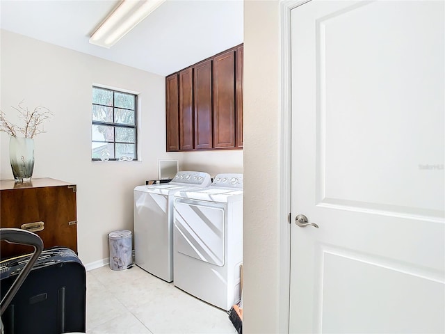 laundry room featuring washing machine and dryer, cabinets, and light tile floors