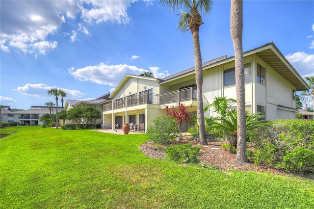 back of house with a balcony and a lawn