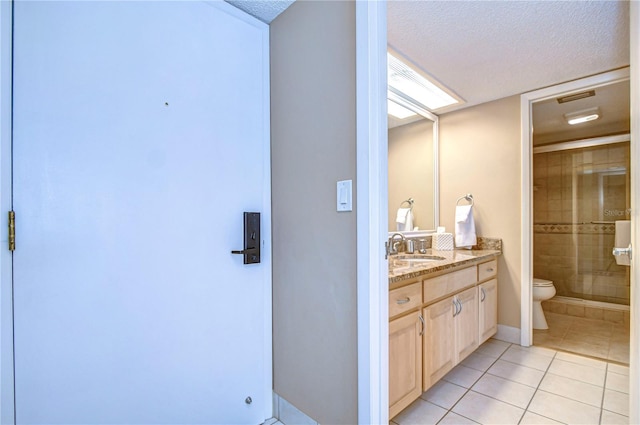 bathroom featuring tile flooring, a textured ceiling, oversized vanity, an enclosed shower, and toilet