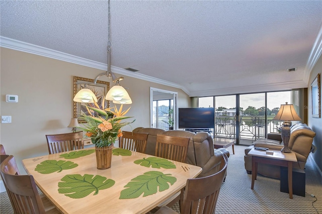 carpeted dining space with a water view, a textured ceiling, and ornamental molding