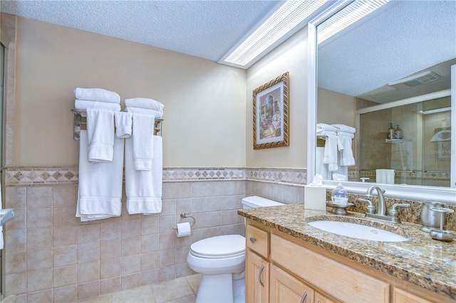 bathroom with tile walls, oversized vanity, tile flooring, toilet, and a textured ceiling