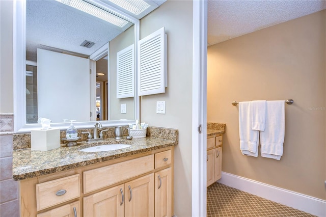 bathroom with a textured ceiling, vanity, and tile flooring