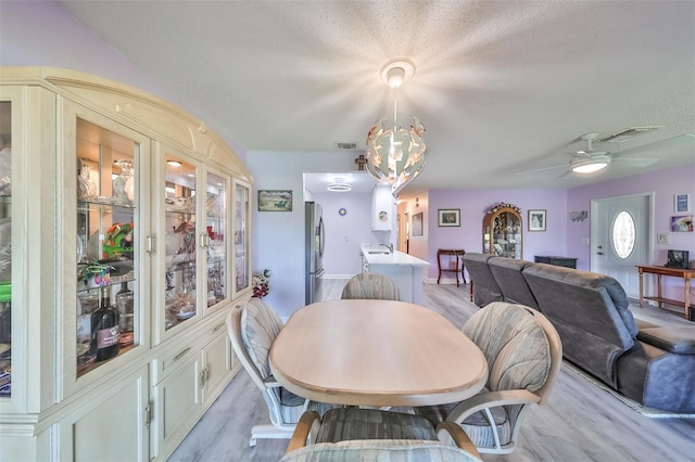 dining area featuring a textured ceiling, visible vents, and light wood-style floors