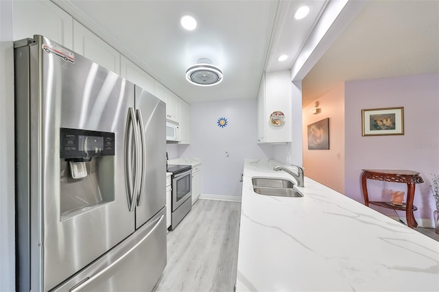 kitchen featuring appliances with stainless steel finishes, white cabinetry, a sink, and light stone counters