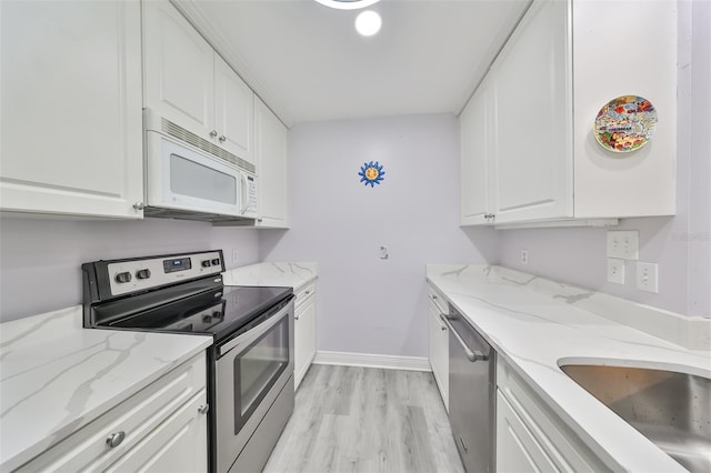 kitchen featuring stainless steel appliances, light wood-style flooring, white cabinetry, a sink, and light stone countertops