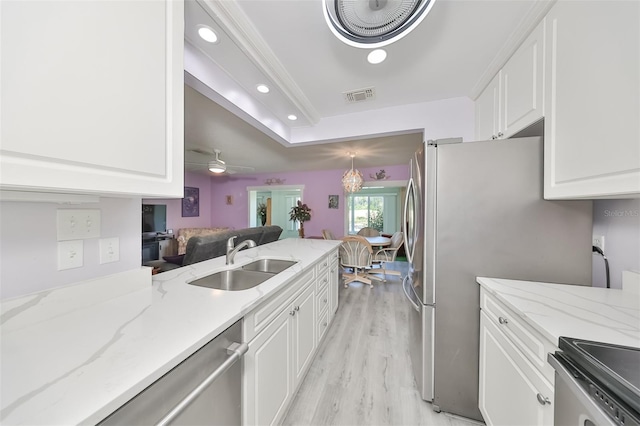 kitchen featuring visible vents, white cabinets, light stone counters, open floor plan, and a sink