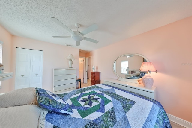 bedroom featuring a textured ceiling, visible vents, baseboards, a ceiling fan, and a closet