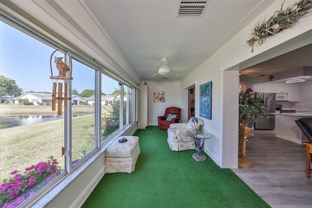 sunroom featuring visible vents, a water view, and ceiling fan