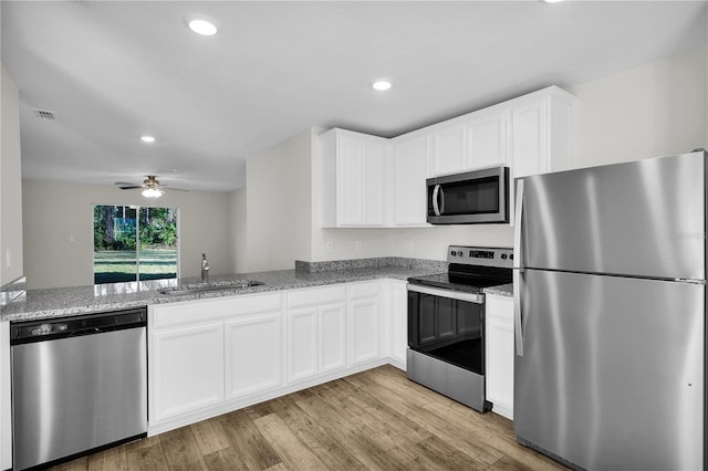 kitchen featuring light hardwood / wood-style flooring, white cabinetry, appliances with stainless steel finishes, light stone counters, and ceiling fan