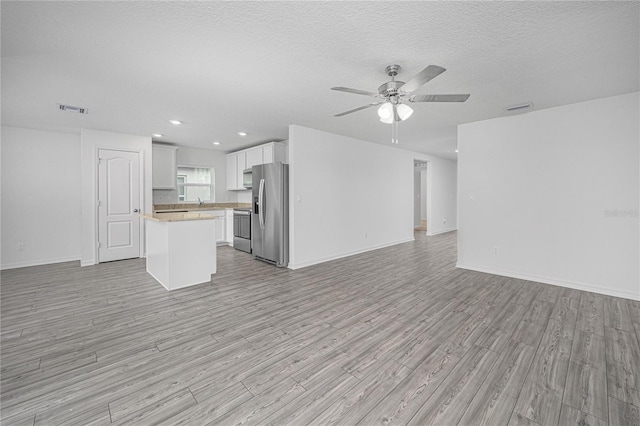 unfurnished living room featuring light hardwood / wood-style floors, a textured ceiling, and ceiling fan