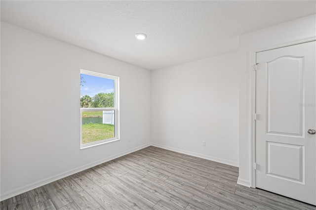 empty room with light hardwood / wood-style flooring and a textured ceiling