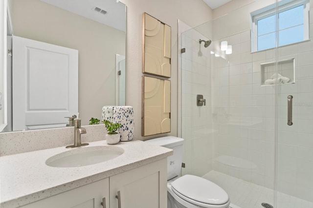 bathroom with vanity, a shower with door, and toilet