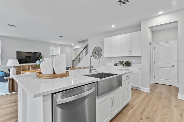 kitchen with white cabinetry, sink, stainless steel dishwasher, and an island with sink