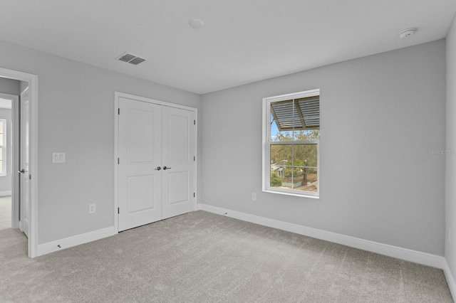 unfurnished bedroom with light carpet and a closet