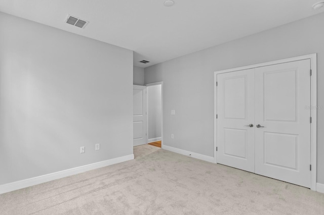 unfurnished bedroom with light carpet and a closet