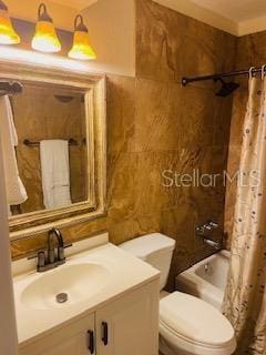 full bath with tile walls, vanity, toilet, and shower / tub combo with curtain