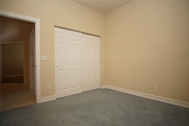 unfurnished bedroom with dark carpet and a closet