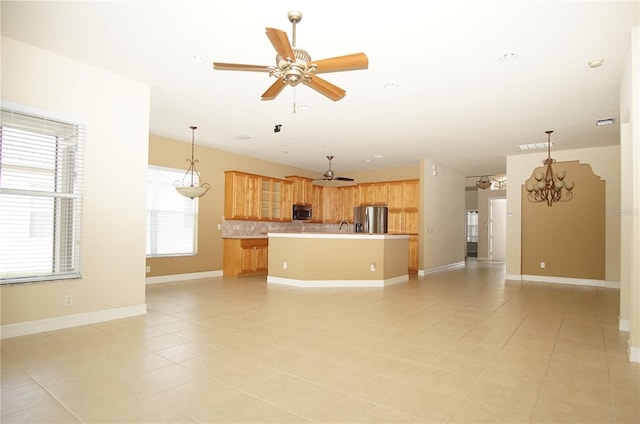 interior space with decorative light fixtures, a kitchen island, stainless steel appliances, ceiling fan with notable chandelier, and backsplash