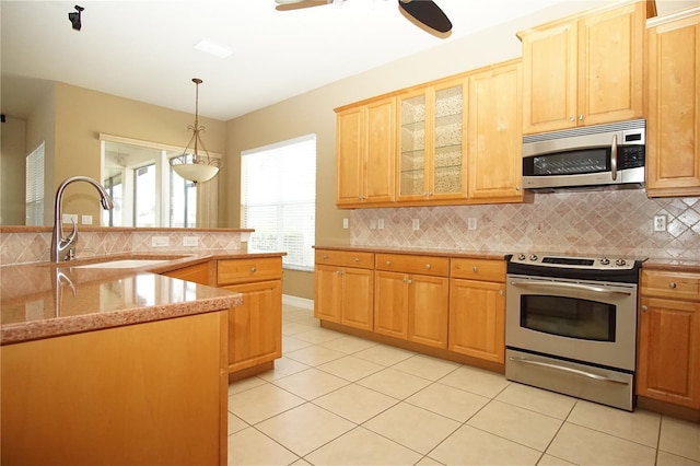 kitchen with tasteful backsplash, stainless steel appliances, sink, light tile patterned floors, and pendant lighting