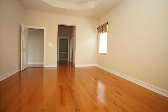 empty room with hardwood / wood-style floors and a raised ceiling