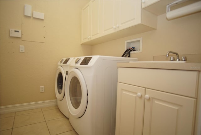 clothes washing area featuring cabinets, light tile patterned floors, and washer and dryer